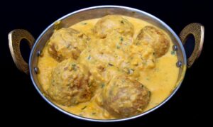 Creamy malai kofta curry with fried vegetable, paneer, and mashed potato balls in rich sauce