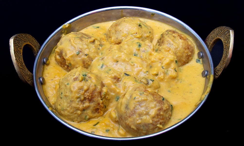Creamy malai kofta curry with fried vegetable, paneer, and mashed potato balls in rich sauce