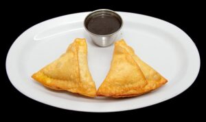 Crispy triangular samosas filled with spiced potatoes and peas, served at Indian Bites in Lyons, Boulder, Longmont, and Estes Park