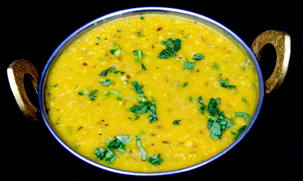 Yellow dal fry cooked with spices, tomatoes, and garnished with fresh cilantro