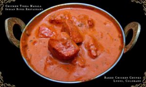 Close-up of Chicken Tikka Masala in a white bowl, garnished with fresh cilantro, showing creamy tomato sauce and tender chicken pieces — authentic Indian cuisine at Indian Bites Lyons, Colorado.