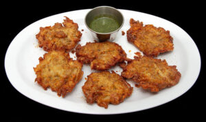 Crispy gluten-free onion pakora served with house-made chutneys at Indian Bites.